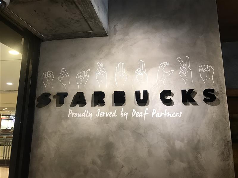 サイニングストアの看板の写真。STARBACKSの文字の上に手話でのアルファベットが描かれている