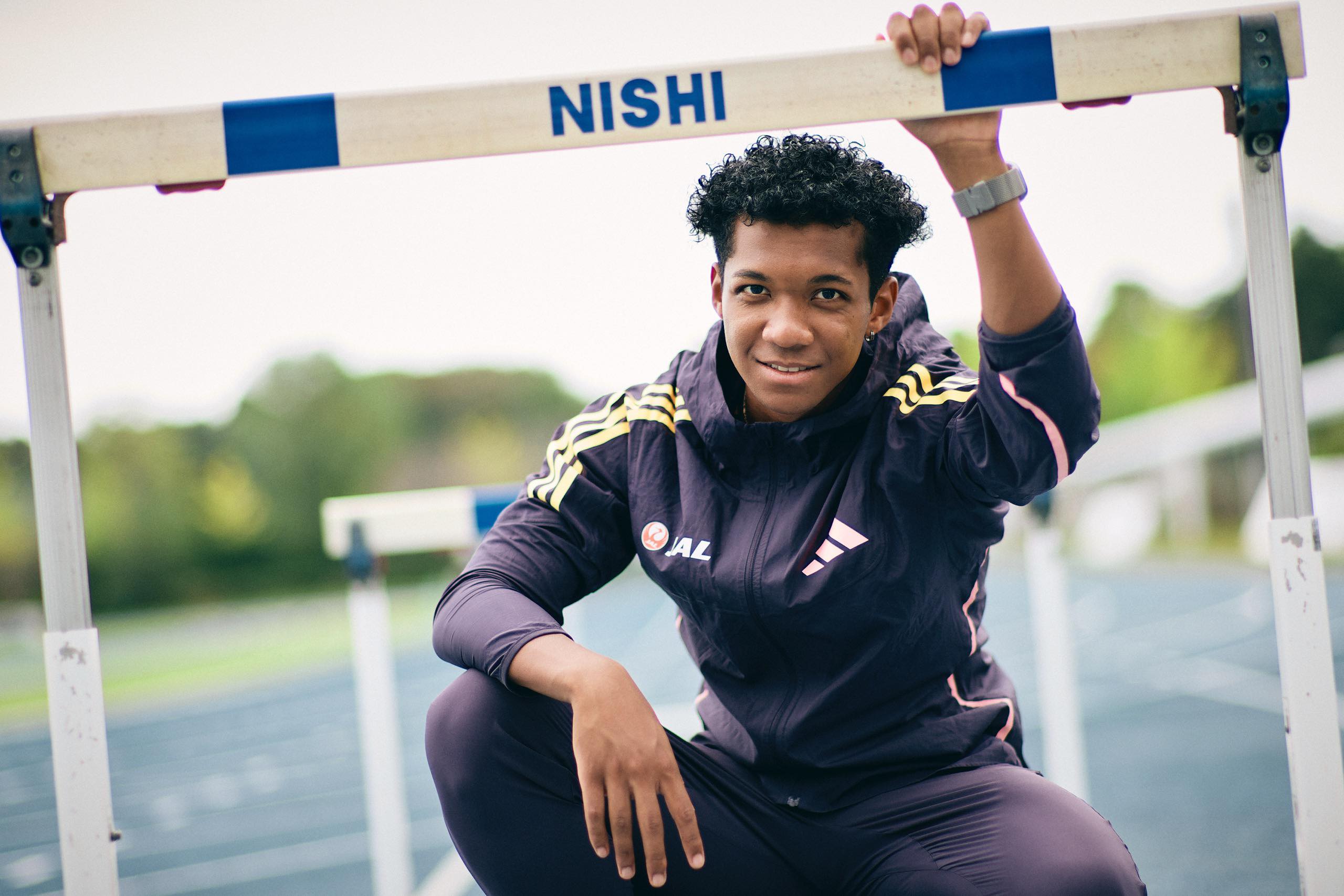 The photo of Muratake squatting and grasping a hurdle with his left hand.