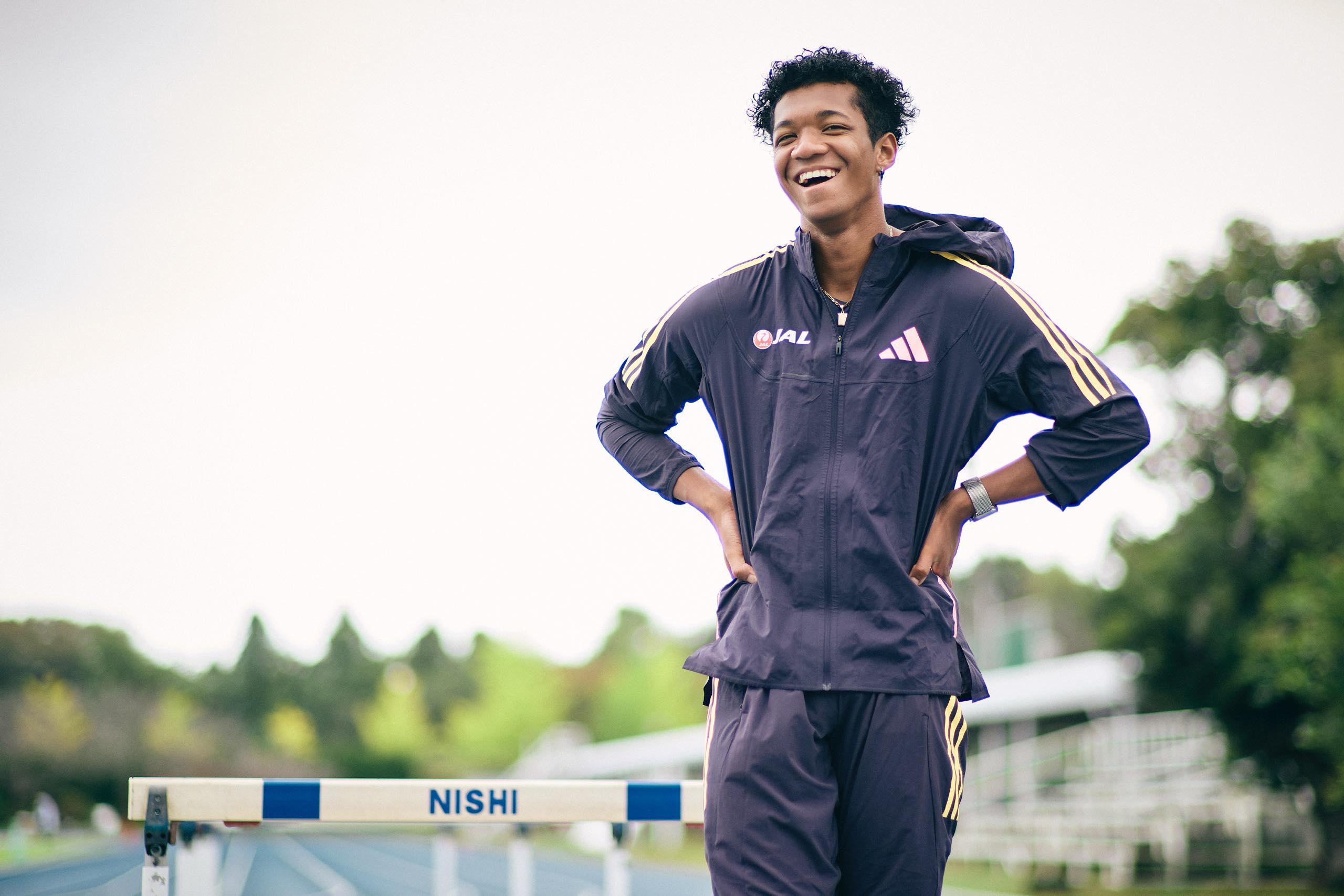 The photo of Muratake smiling in front of the hurdles.