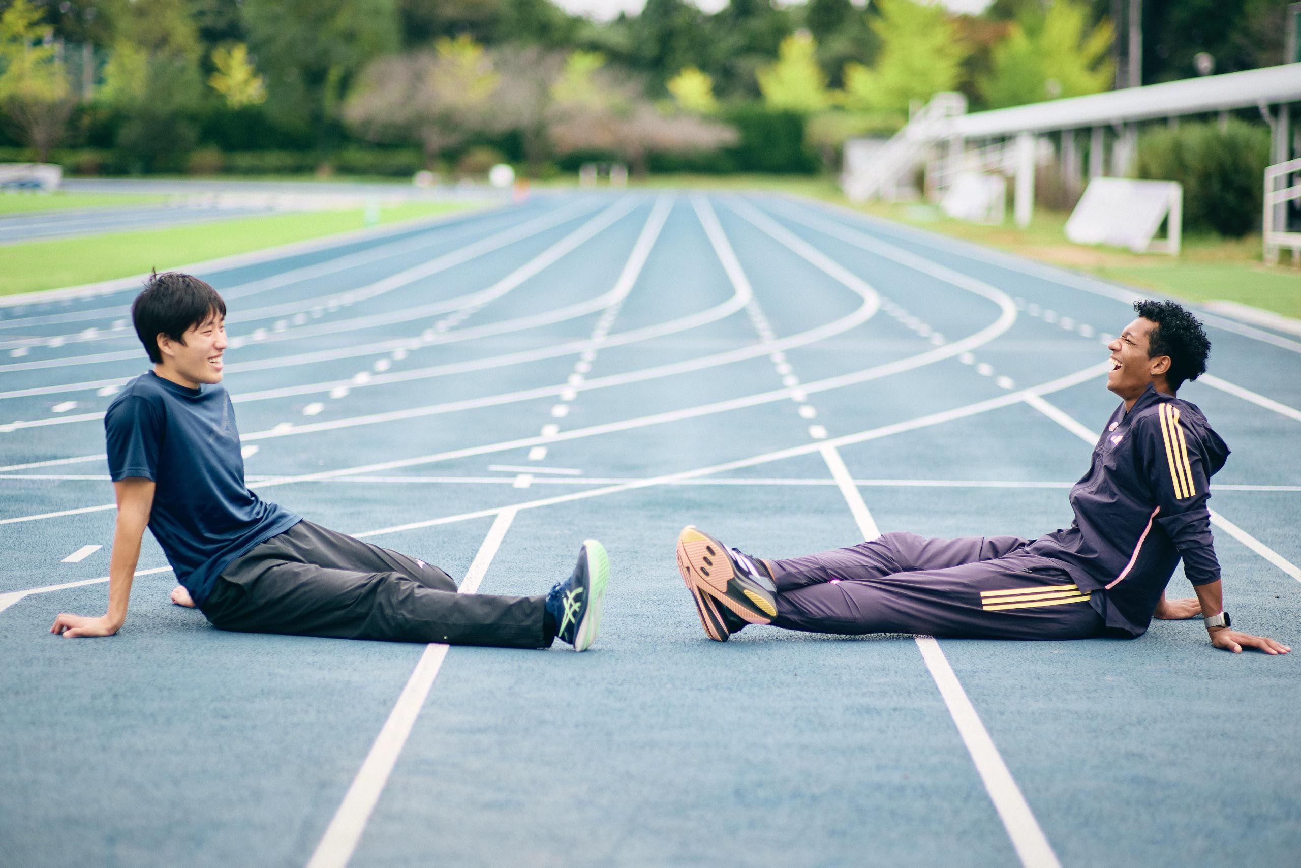 The photo of Muratake sitting on the track and laughing with other athletes.