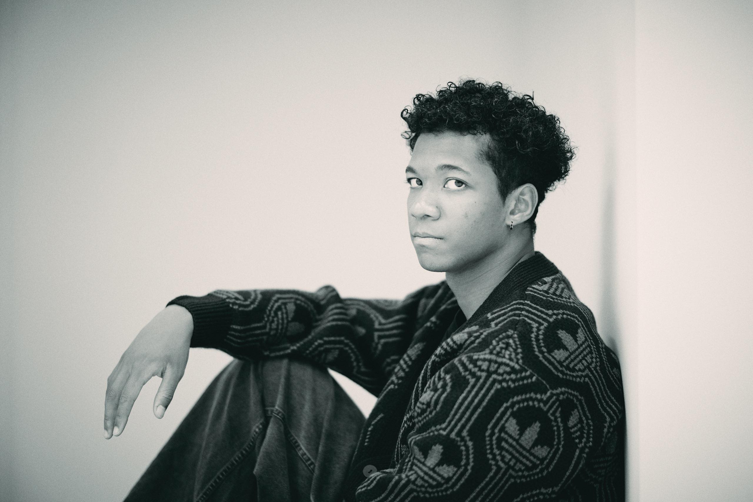 Black and white photo of Muratake sitting and on one knee bent, looking at us.