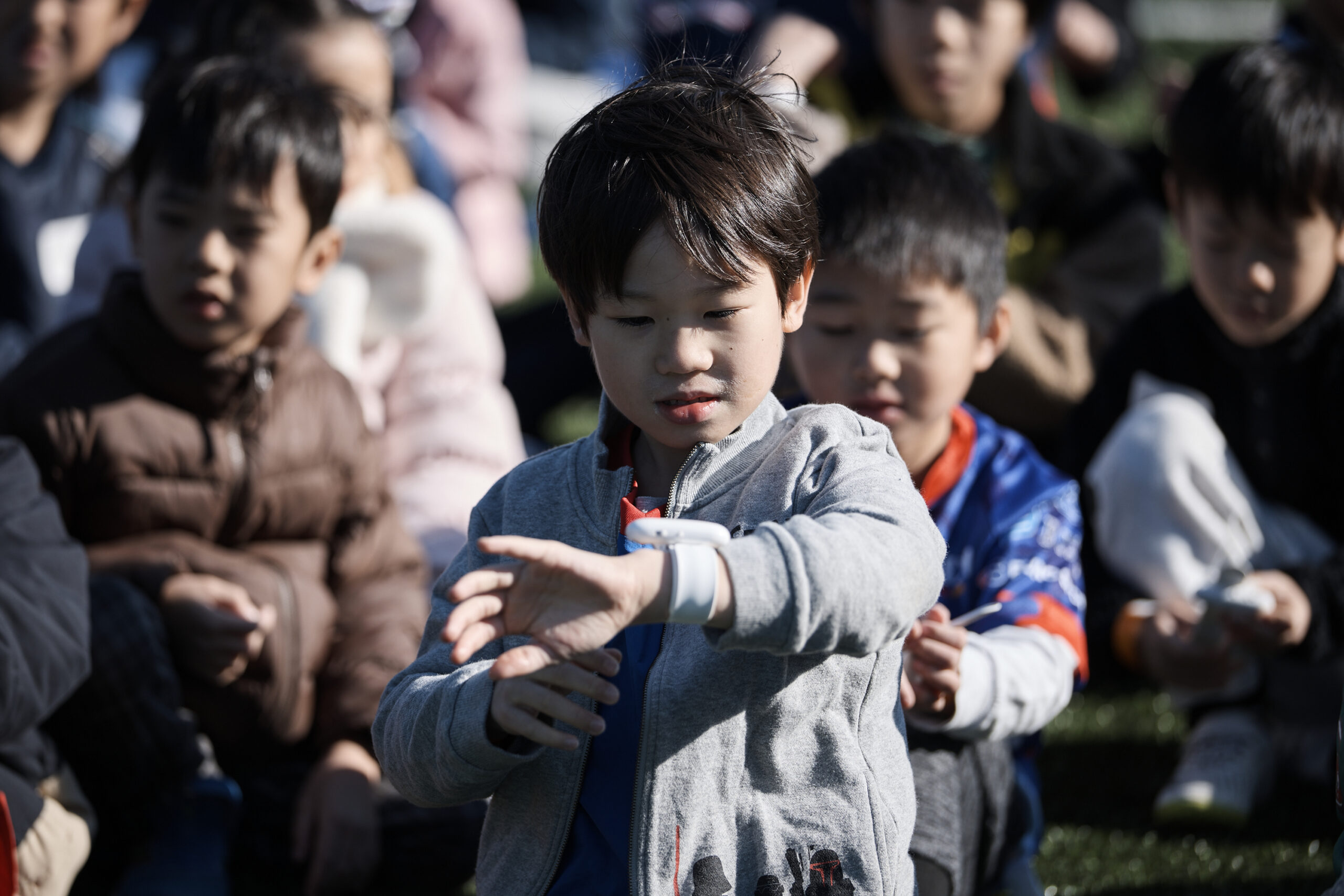 左腕にOntennaをつけて見つめている参加者の男の子の写真