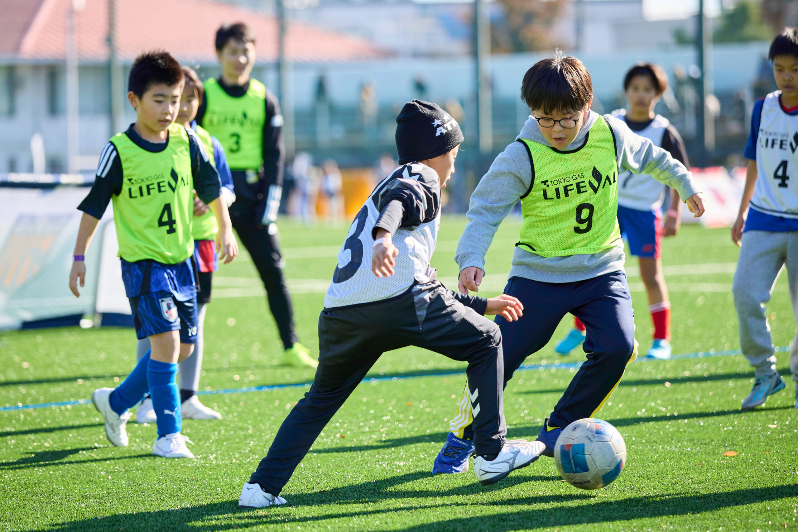 黄色いビブスの男の子からボールを奪おうとしている白いビブスの男の子の写真