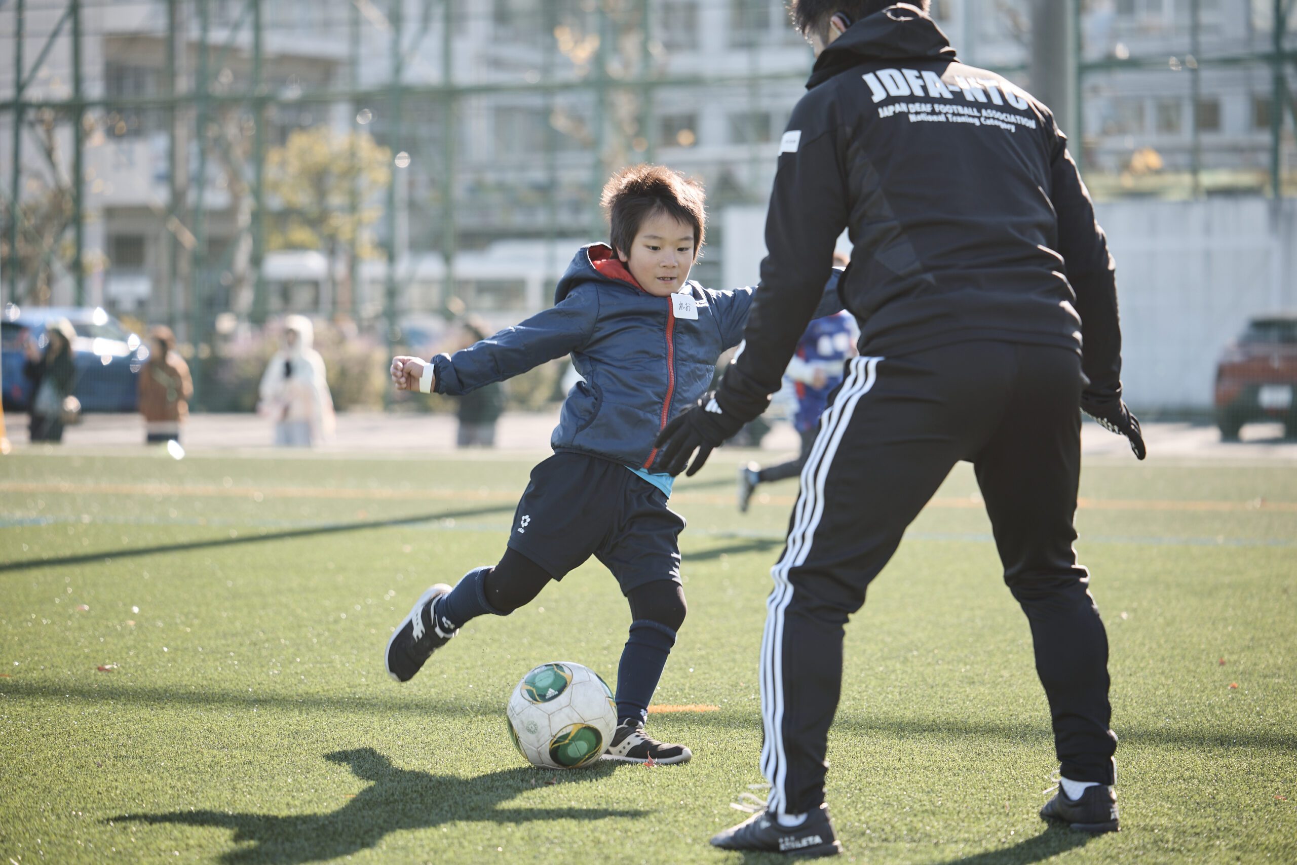 ブロックしているデフサッカー選手に挑んでいる男の子の写真