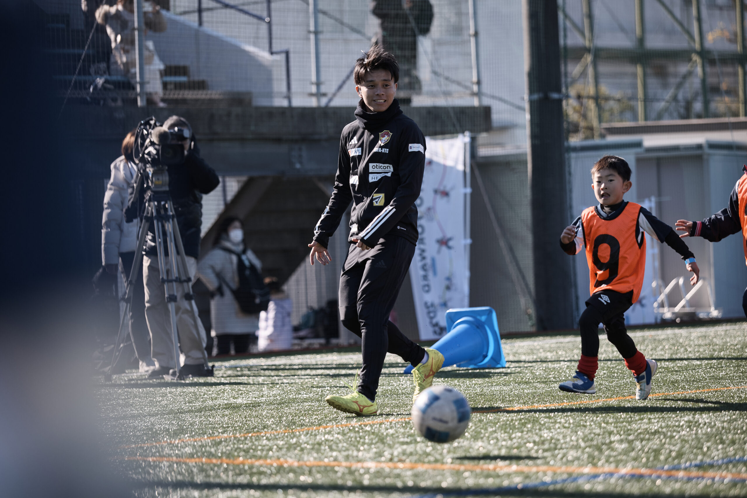 子供たちと一緒にボールを追いかけている宗澤選手の写真