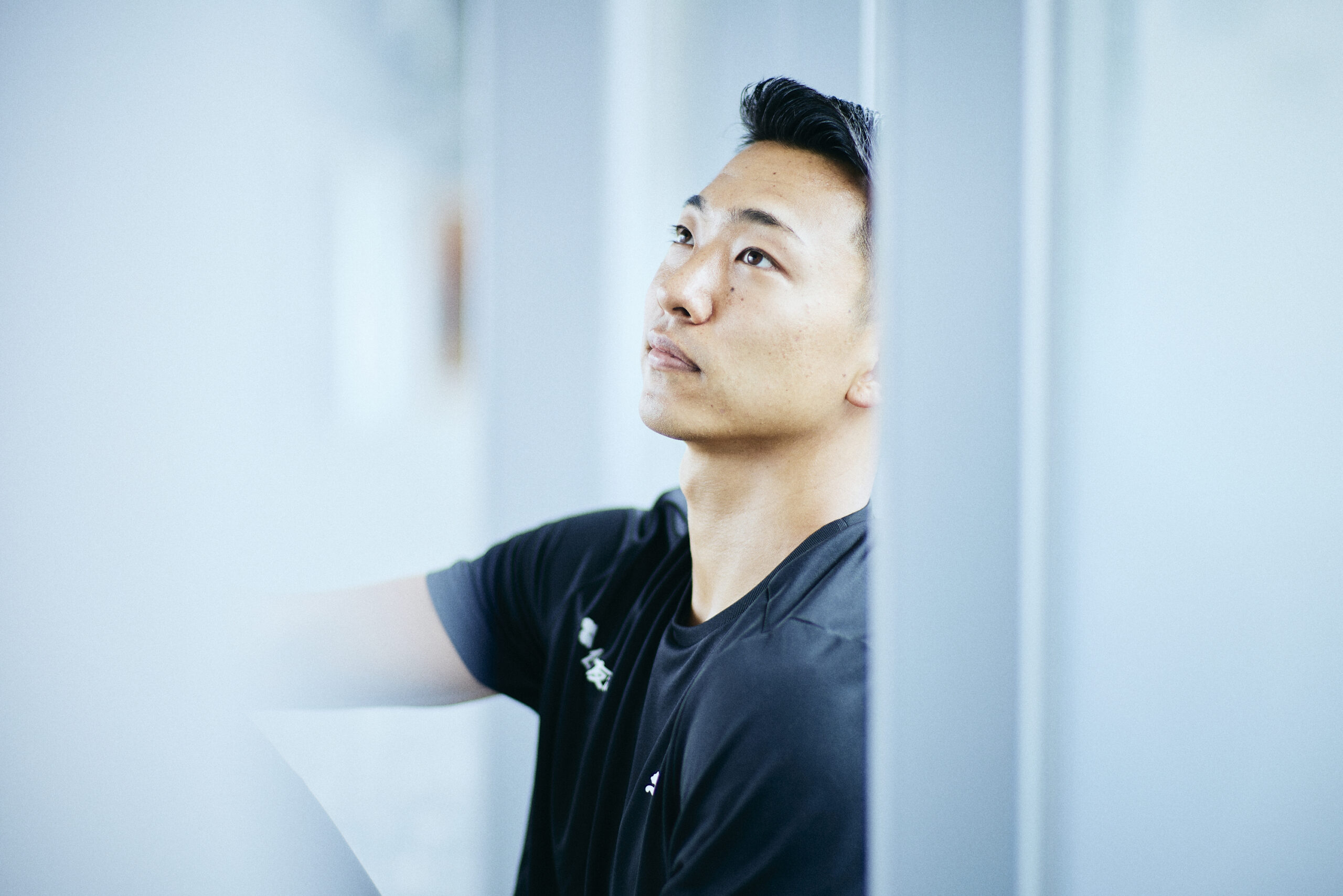 The photo of Maruyama leaning against a window and staring diagonally upward.