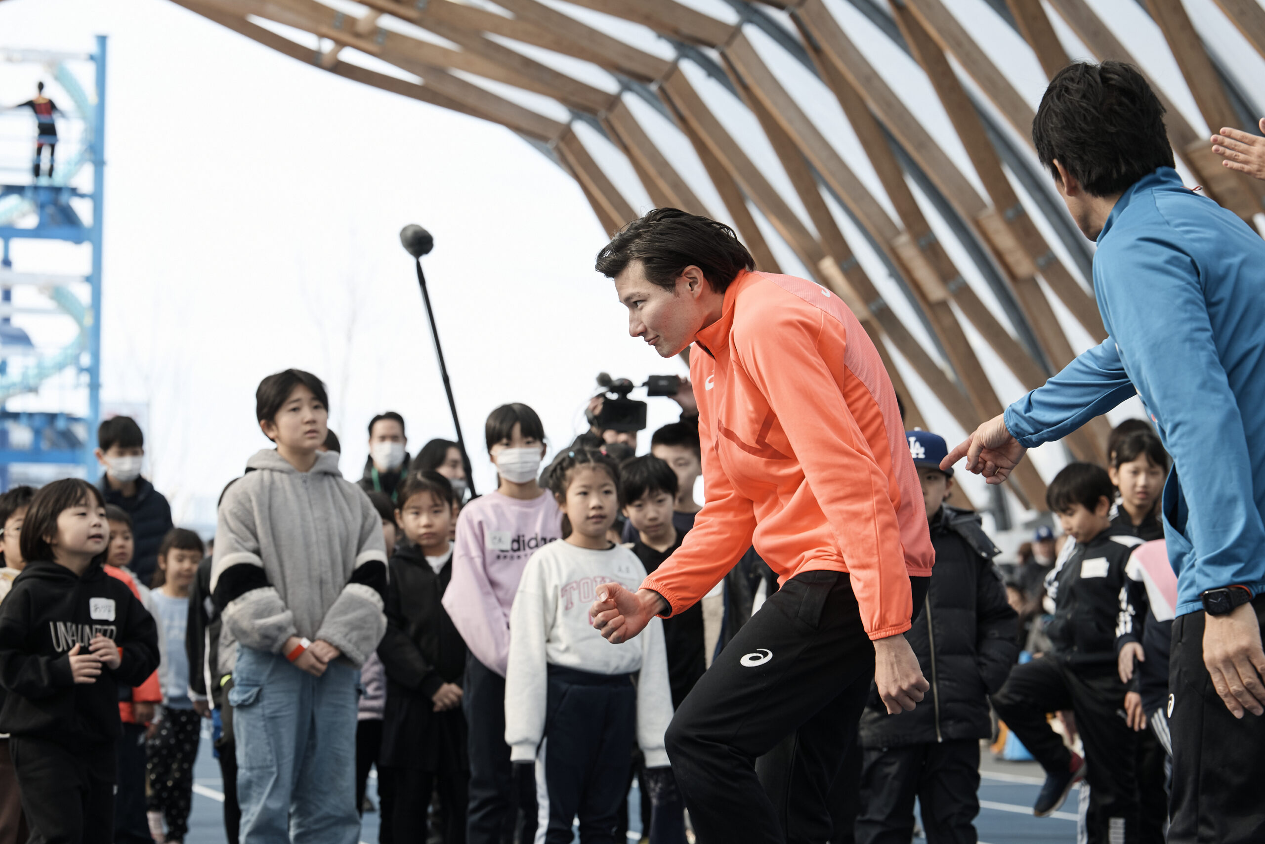 子供たちの前で背中を丸めている山田選手の写真