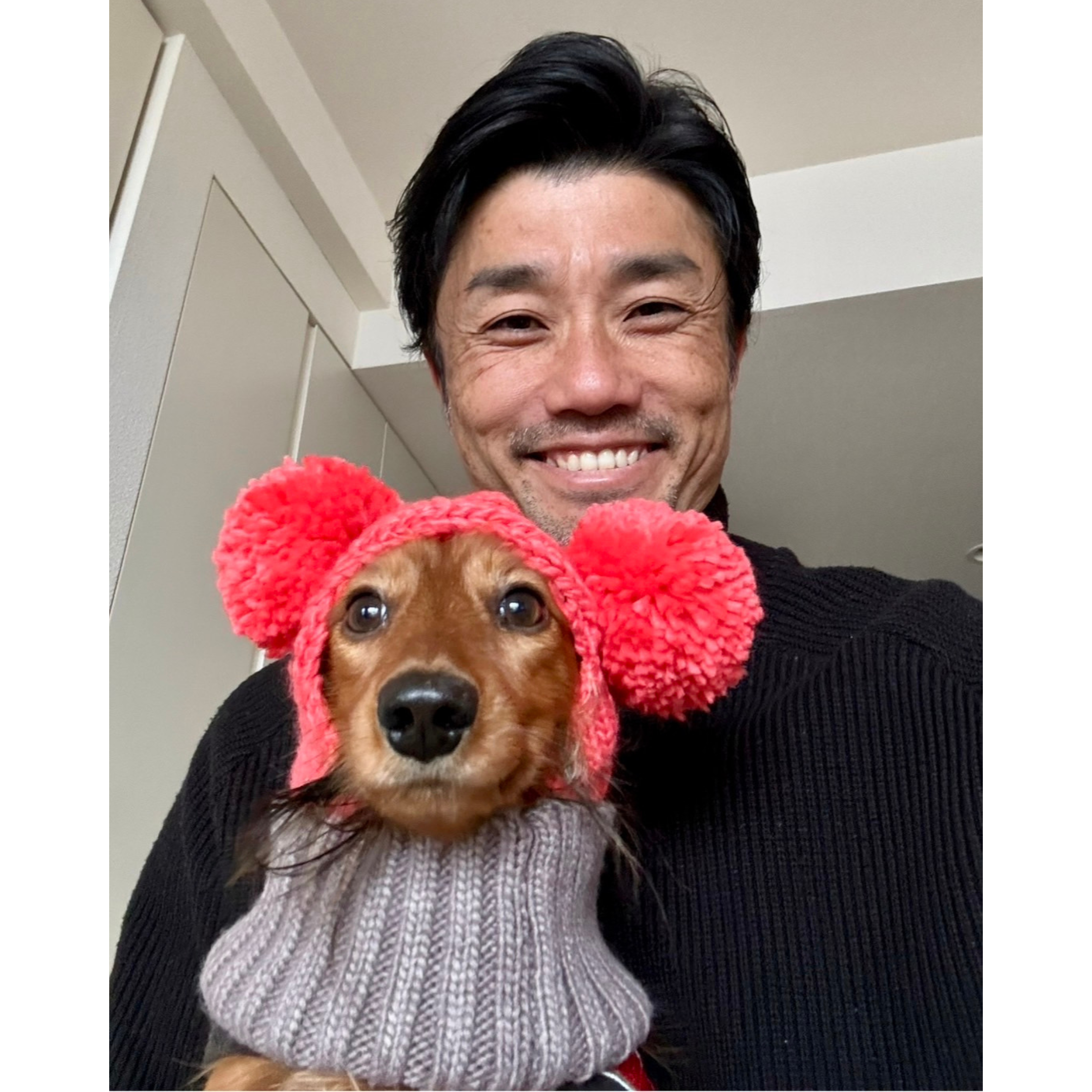 A photo of Suetsugu and his dog wearing a woolen red earmuff.