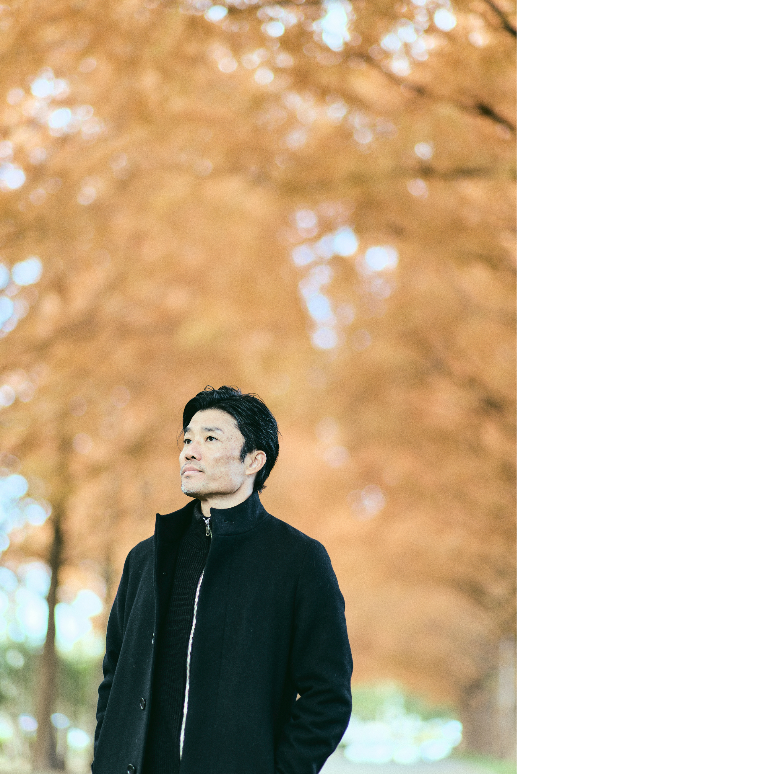 A photo of Suetsugu staring into the distance with a ginkgo tree in the background.