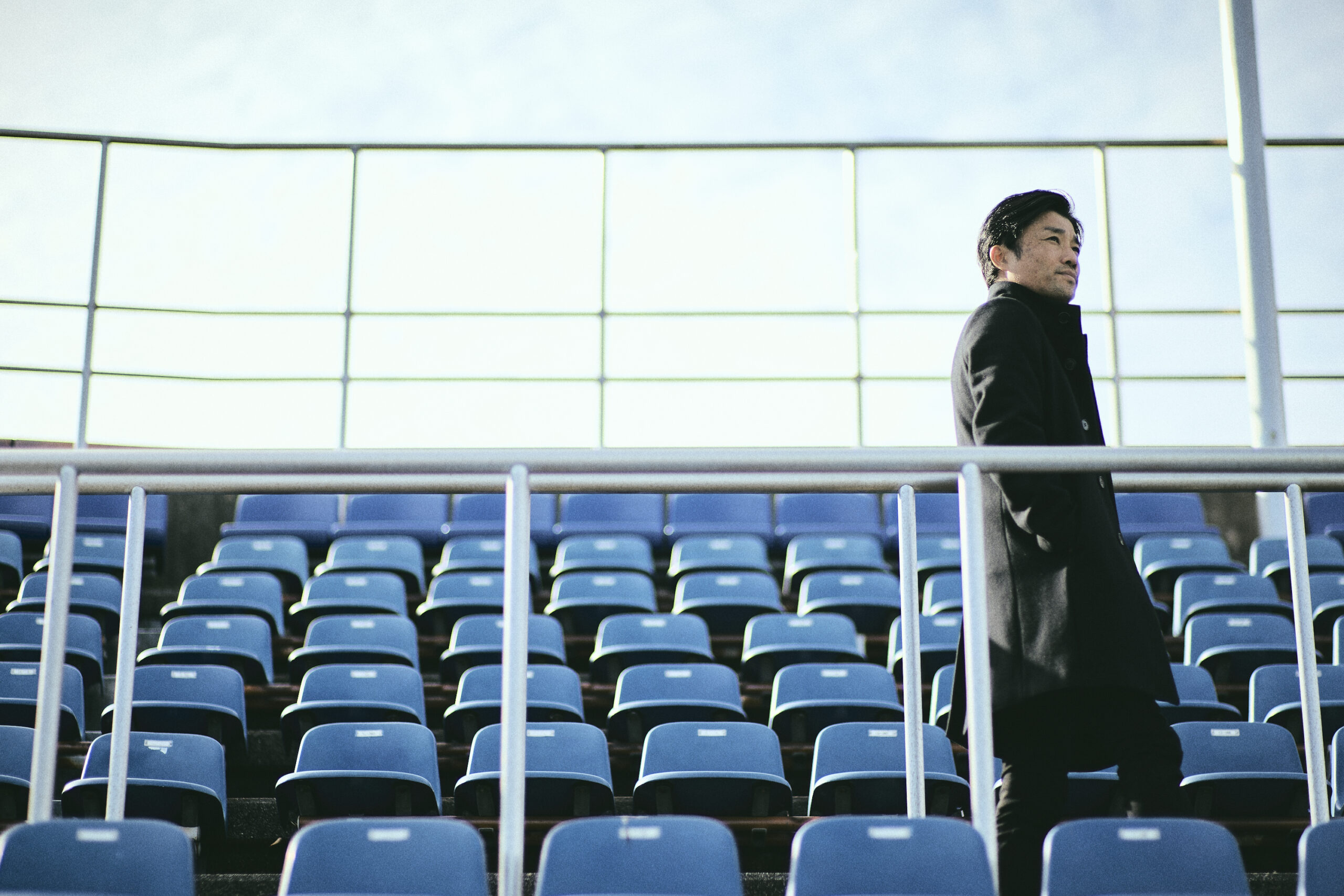 A photo of Suetsugu standing in the audience, staring into the distance.