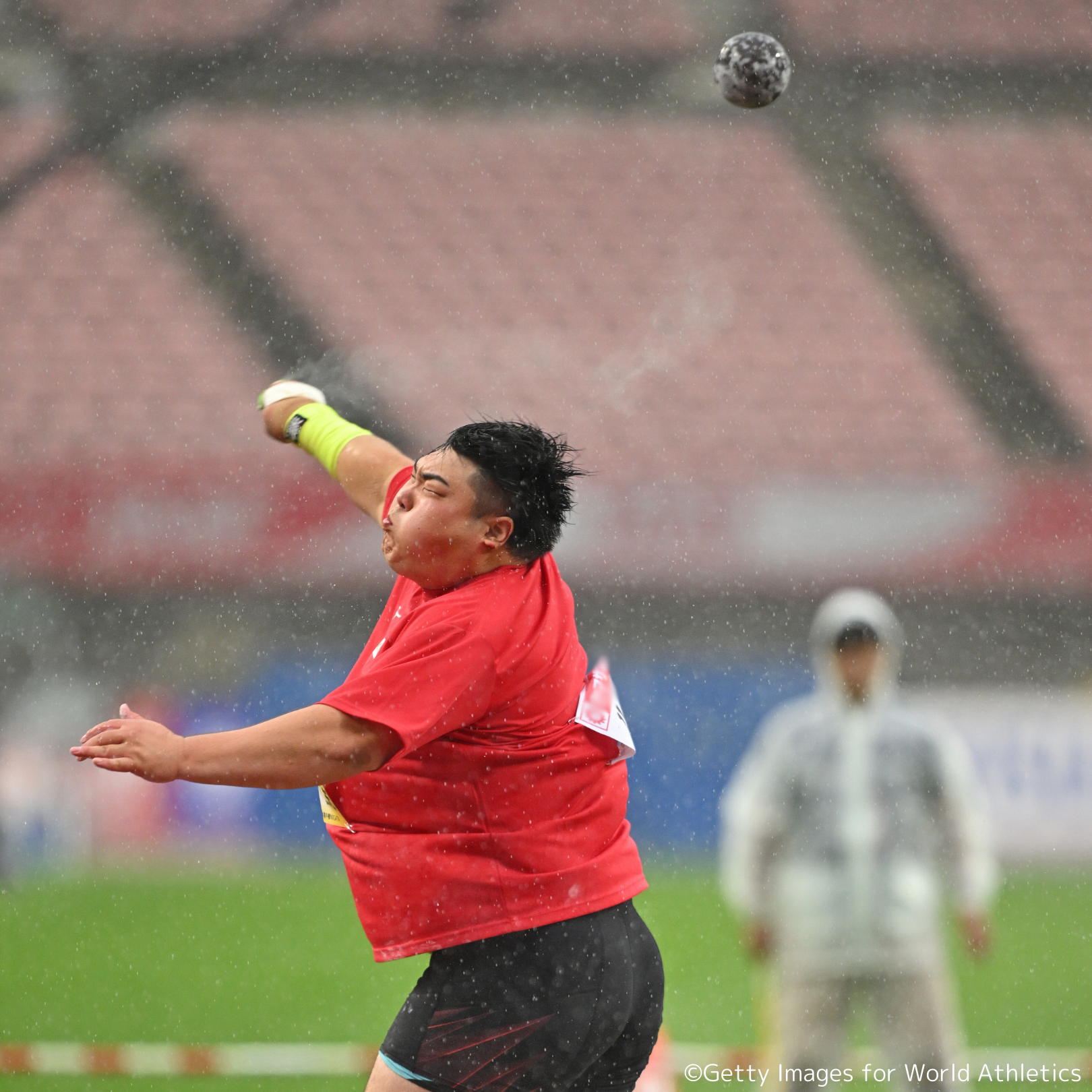 雨の中、試合で砲丸を投げている奥村選手の写真