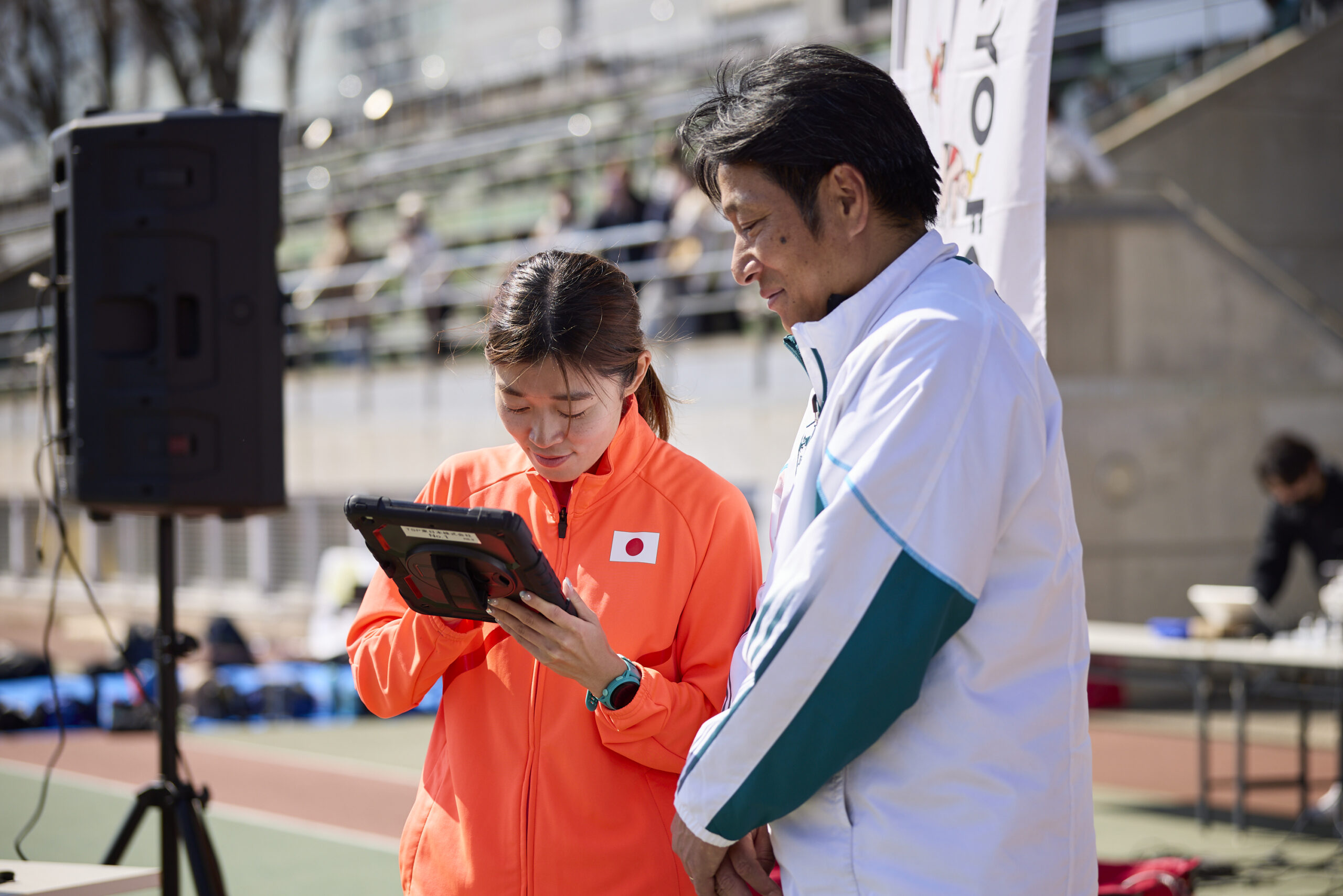 タブレットに文字を入力している岡田選手とその横でタブレットを見ている原監督の写真