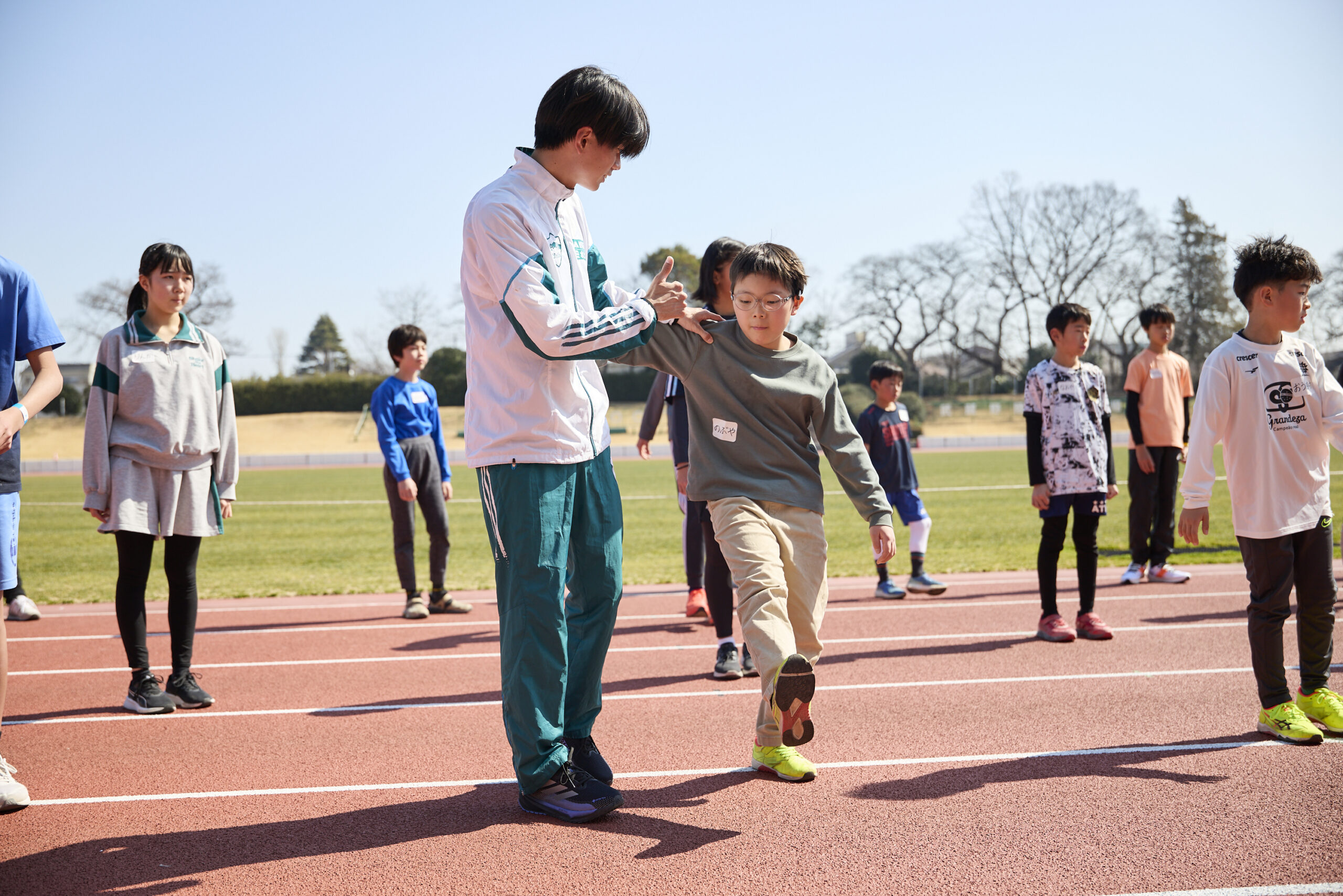 右足をあげている参加者の肩を支えている若林選手の写真